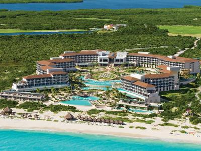 Grande resort sul lungomare con piscine circondate da vegetazione e mare turchese.