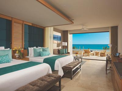 Camera d'hotel spaziosa con due letti, balcone con vista mare e arredo moderno.