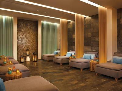 Sala spa accogliente con lettini, candele e illuminazione calda per un'atmosfera rilassante.