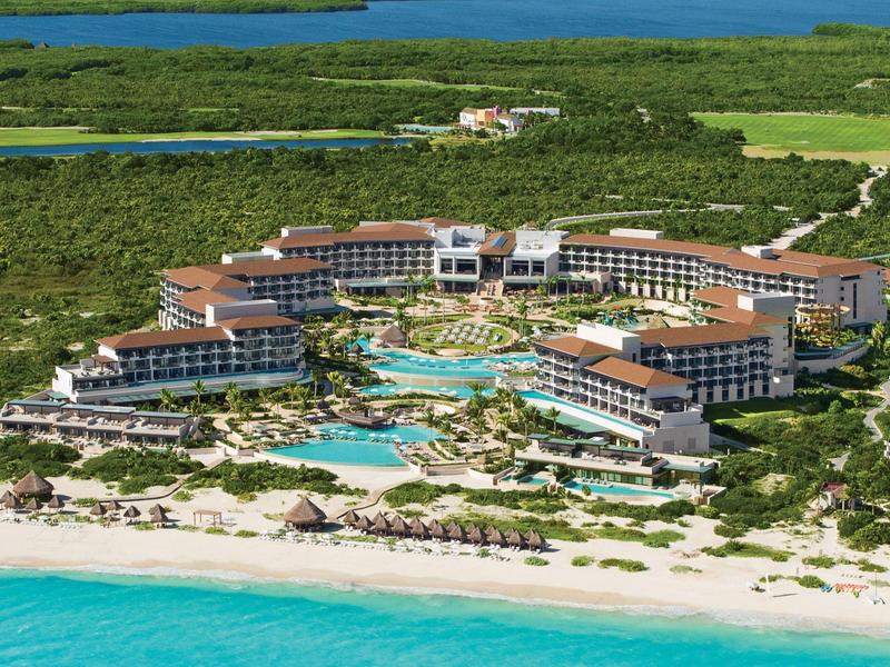 Grande resort sul lungomare con piscine circondate da vegetazione e mare turchese.