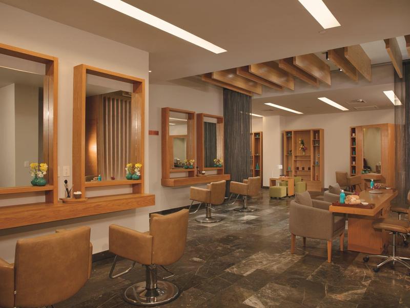 Salone moderno con poltrone in pelle, specchi in legno e pavimento in pietra.