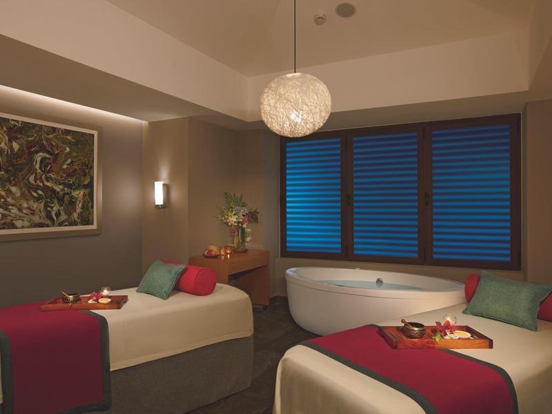 Accogliente stanza spa con due lettini da massaggio, vasca da bagno e illuminazione d'atmosfera.