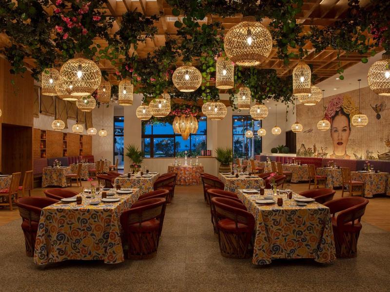 Ristorante accogliente con tovaglie floreali, lampade sospese e luce calda.