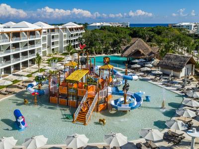 Hotel con grande parco acquatico, scivoli e lettini in ambiente tropicale.