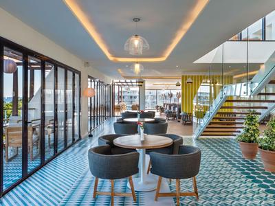 Ristorante moderno dell'hotel con pavimento in piastrelle blu a motivo, sedie nere e grandi finestre in vetro.