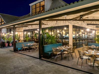 Osvětlená restaurace s venkovním posezením a moderní atmosférou v noci.