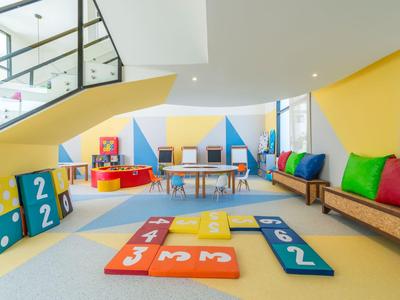 Area giochi colorata per bambini con blocchi imbottiti e cuscini in una stanza luminosa.