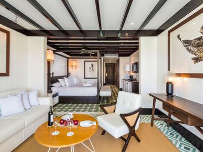 Camera d'hotel elegante con letto, divano, scrivania e immagini decorative di animali alle pareti.