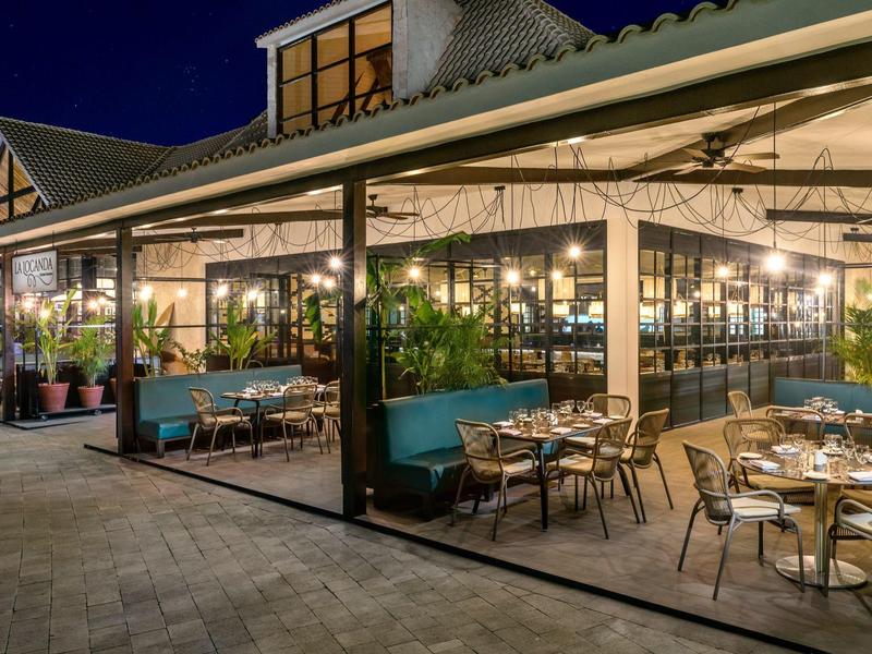 Accogliente terrazza esterna di un ristorante con tavoli apparecchiati e illuminazione d'atmosfera di notte.