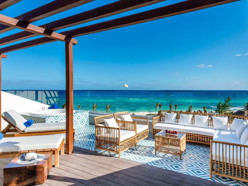 Terrazza aperta con mobili in rattan e vista mare in una giornata serena.