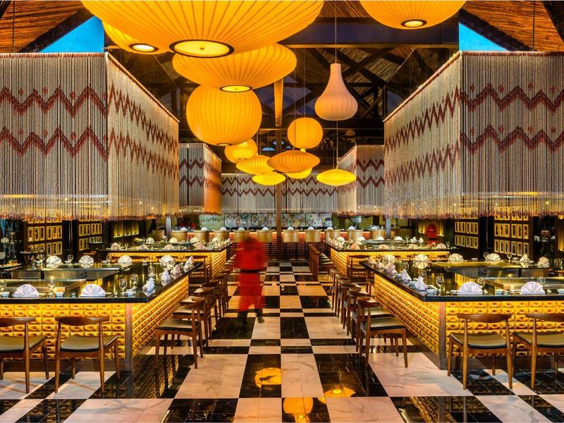 Ristorante elegante con lampade a sospensione gialle e pavimento a motivo bianco e nero in un hotel.