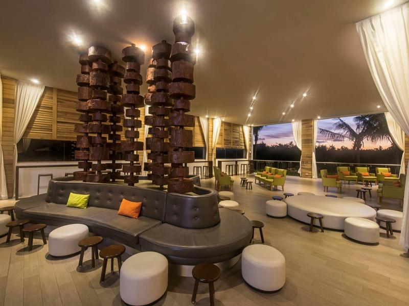 Salon extérieur moderne avec sculpture en bois unique, sièges rembourrés et vue sur le coucher du soleil.