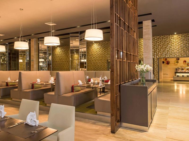 Restaurant d'hôtel moderne avec banquettes confortables, tables, éclairage chaleureux et décoration élégante.