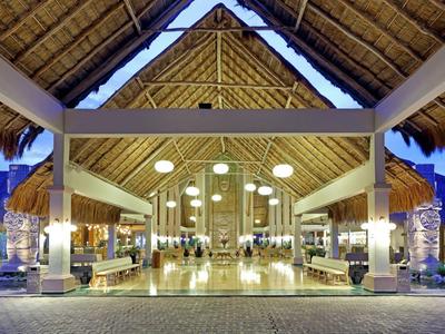 Ingresso ampio e luminoso di un resort tropicale con tetto di paglia.