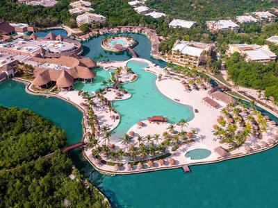 Veduta aerea di un resort con piscina a forma libera circondata da vegetazione.