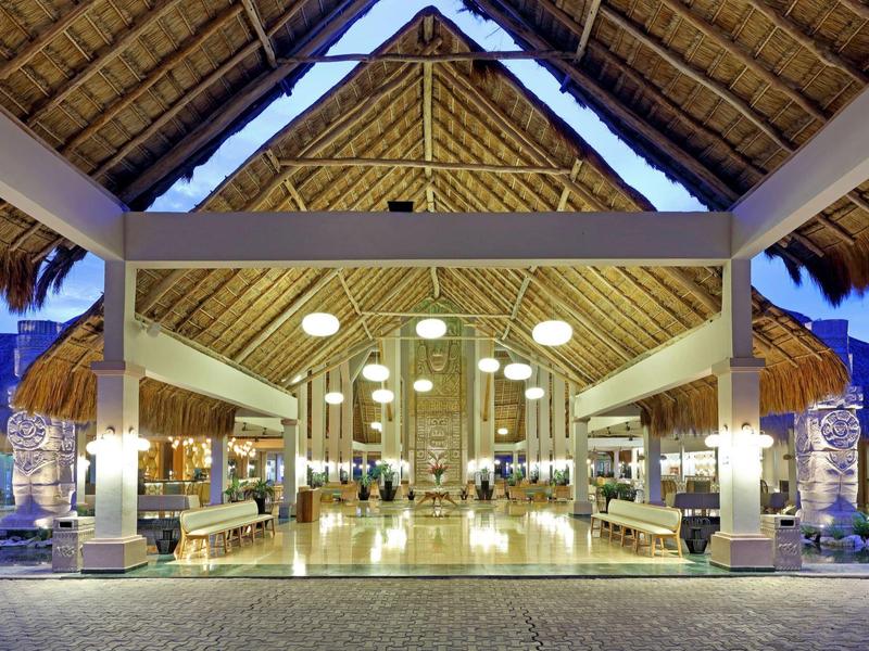 Ingresso ampio e luminoso di un resort tropicale con tetto di paglia.