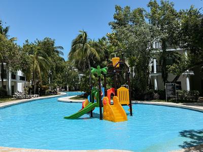 Parco giochi acquatico per bambini con scivoli in una piscina dell'hotel, circondato da palme.
