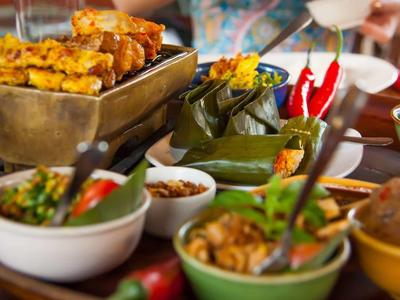 Vassoio con diverse ciotole di piatti asiatici speziati, tra cui spiedini e peperoncini.