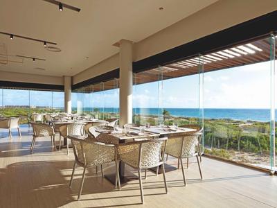 Ristorante con vista panoramica sul mare tramite grandi finestre in vetro.