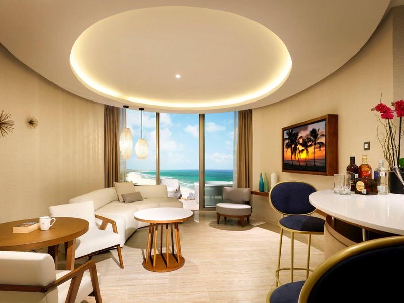 Camera d'hotel elegante con vista sul mare, area salotto moderna e illuminazione elegante.