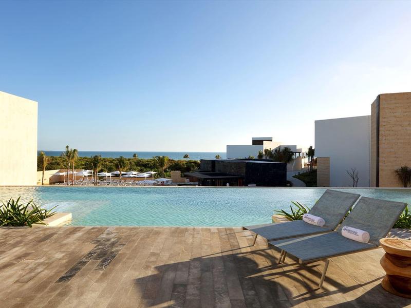 Piscina dell'hotel con vista sul mare, lettini e cielo azzurro sullo sfondo.