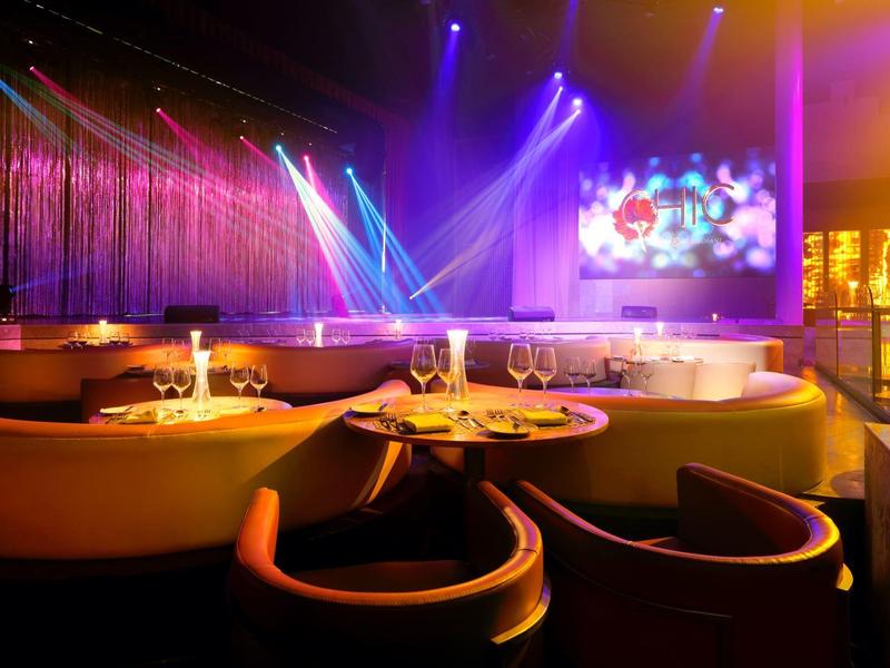 Bar moderna con posti a sedere lounge, tavoli e illuminazione colorata del palco