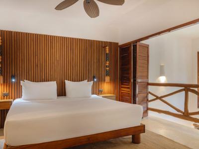 Modern eingerichtetes Hotelzimmer mit Doppelbett, Holzverkleidung und Deckenventilator.