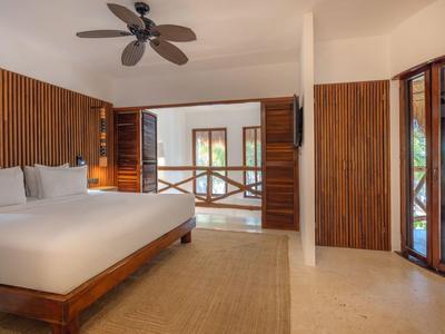Modernes Hotelzimmer mit großem Bett, Holzvertäfelungen und Blick auf Balkon und Gebäude.