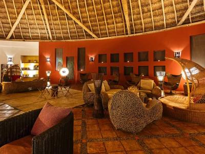 Salon d'hôtel confortable avec des couleurs chaudes et des meubles en osier uniques sous un plafond en bois.