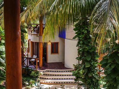 Una camera d'hotel tropicale con pareti bianche, scale e vegetazione verde rigogliosa.