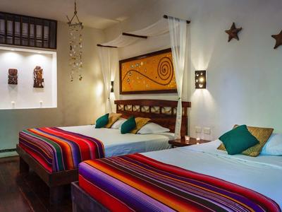 Chambre d'hôtel confortable avec deux lits, coussins colorés et étoiles décoratives au mur.