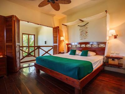 Chambre confortable avec grand lit, meubles en bois et vue sur balcon.