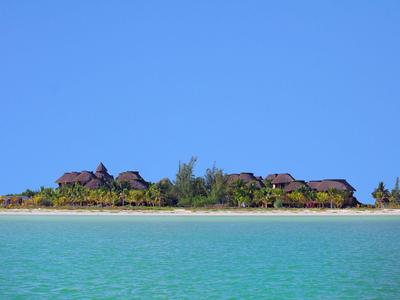 Weit entfernte Hotelgebäude am Strand mit klarem blauem Himmel und türkisfarbenem Wasser.