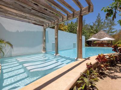 Moderne Poolanlage mit überdachtem Bereich, Pflanzen und Sonnenschirmen in tropischer Umgebung.