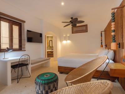 Helles Hotelzimmer mit Doppelbett, Schreibtisch, Sitzgelegenheiten und moderner Wanddeko.