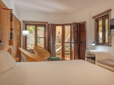 Helles Hotelzimmer mit großem Bett, Holzdekoration und Balkon mit Außenblick.