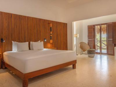 Modernes Hotelzimmer mit großem Bett, Holzpaneelen und offenem Zugang zur Terrasse.