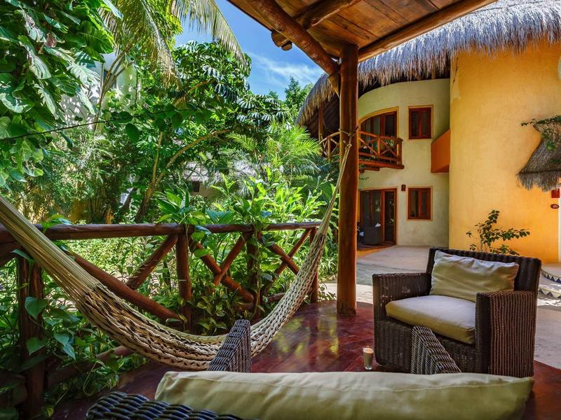 Terrasse confortable avec hamac et fauteuils entourée d'une végétation luxuriante.