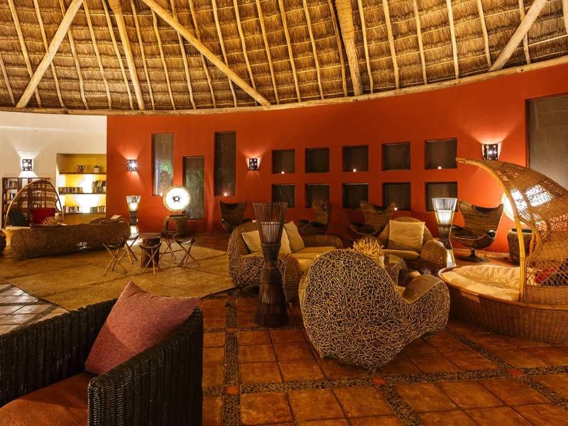 Salon d'hôtel confortable avec des couleurs chaudes et des meubles en osier uniques sous un plafond en bois.