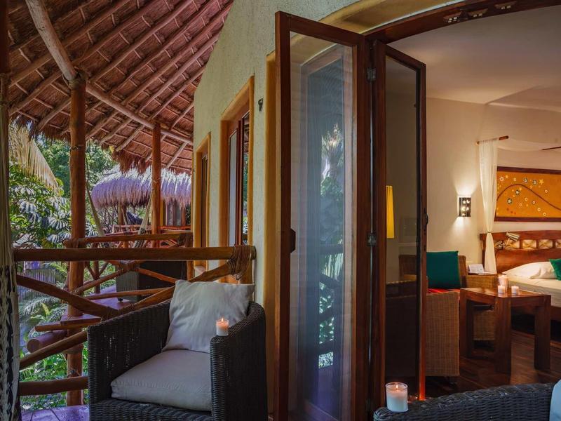 Coin salon confortable sur une terrasse couverte avec vue sur la végétation tropicale.