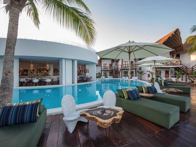 Moderner Poolbereich mit Sitzmöbeln und Sonnenschirmen in einem tropischen Hotel.