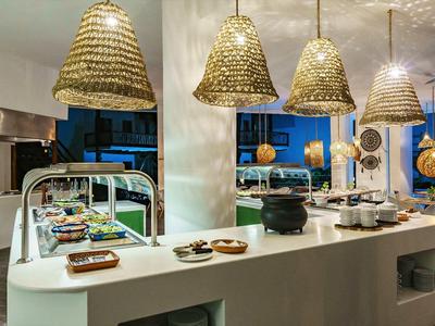 Buffet moderne avec comptoir blanc incurvé et lampes suspendues tissées.