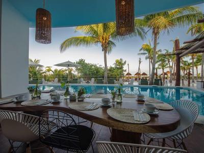 Tisch mit Geschirr und Stühlen an einem Pool mit Palmen im Hintergrund.