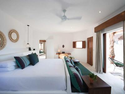 Chambre d'hôtel lumineuse avec grand lit, canapé, ventilateur de plafond et accès à une terrasse ou un balcon.