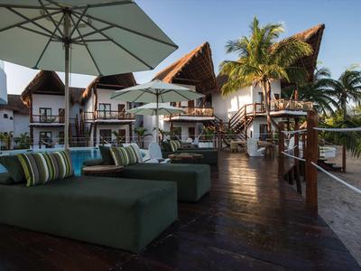 Moderner Außenbereich eines Hotels mit Sonnenschirmen, Liegen und tropischer Vegetation am Abend.