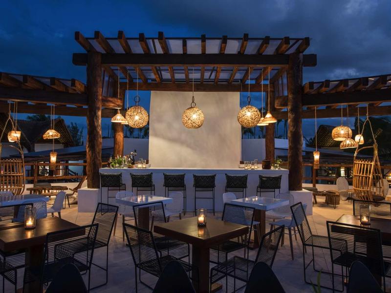 Bar d'hôtel élégante avec éclairage moderne et sièges extérieurs la nuit.