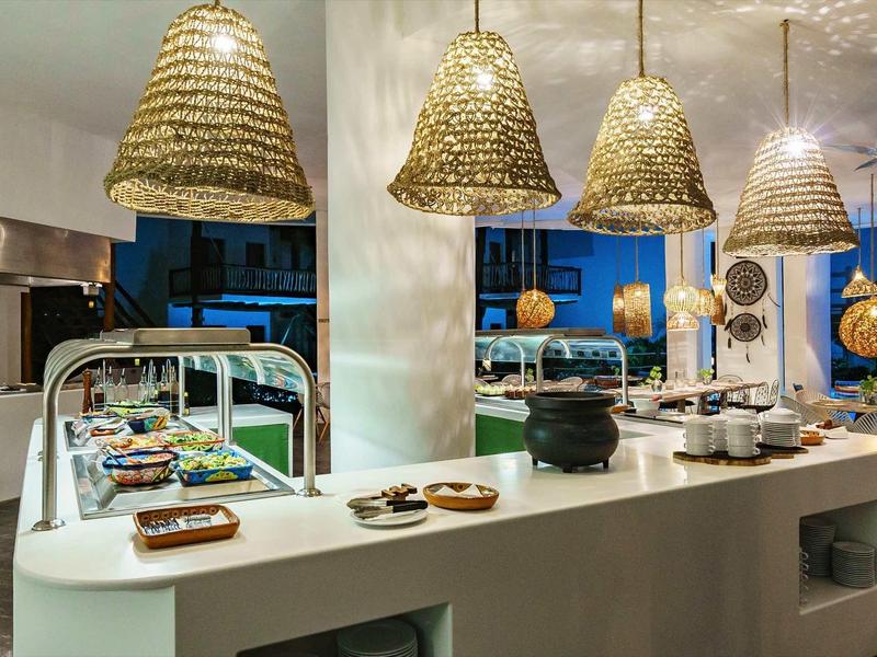 Buffet moderne avec comptoir blanc incurvé et lampes suspendues tissées.