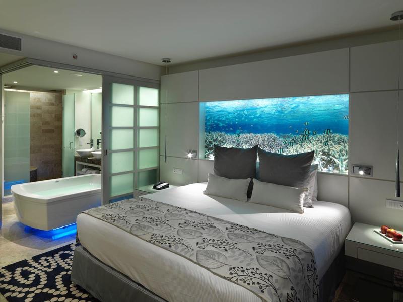 Camera d'hotel moderna con letto matrimoniale, illuminazione d'ambiente e bagno aperto.