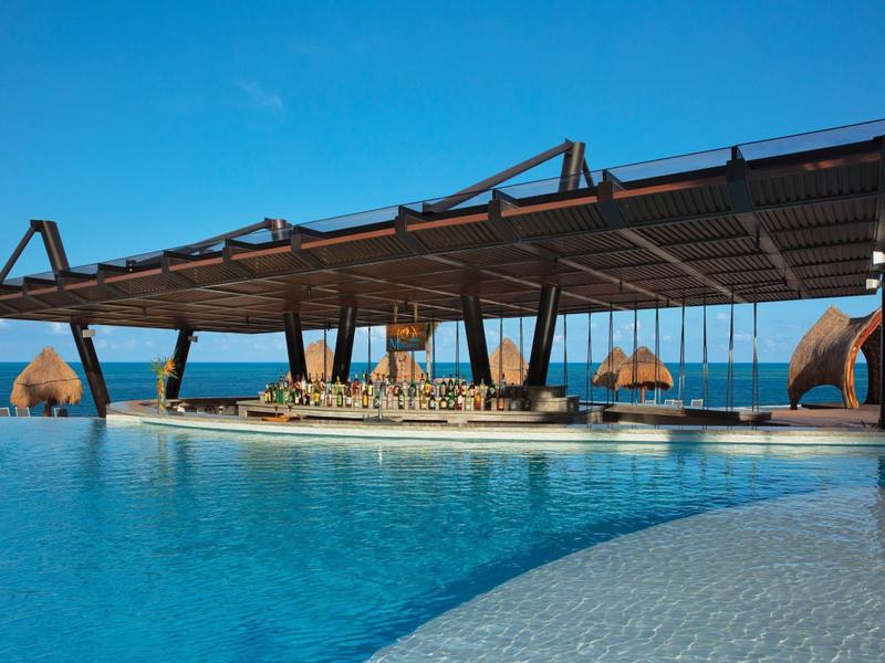Padiglione moderno sopra una piscina con vista sul mare e cielo azzurro.