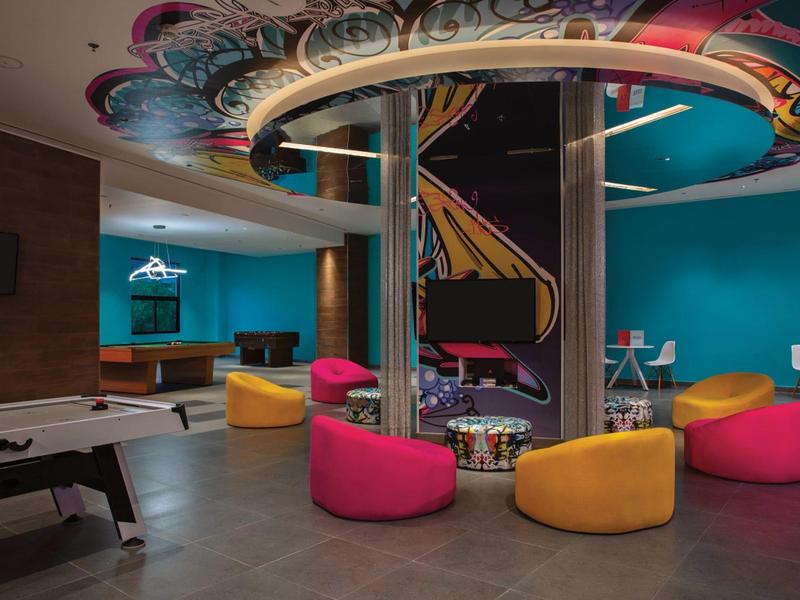 Lounge colorata con puff moderni e calcio balilla in una sala giochi dell'hotel.